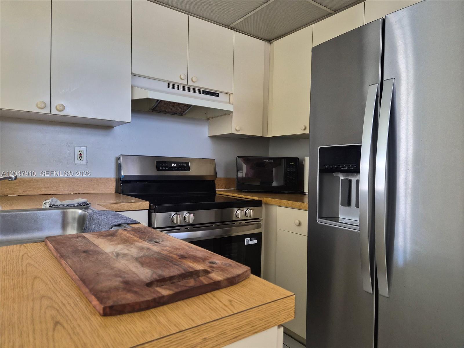 A kitchen features white cabinets, stainless steel appliances, and wood-look laminate countertops — 14913 SW 104th St # 23, Miami FL 33196, MIAMI, FL