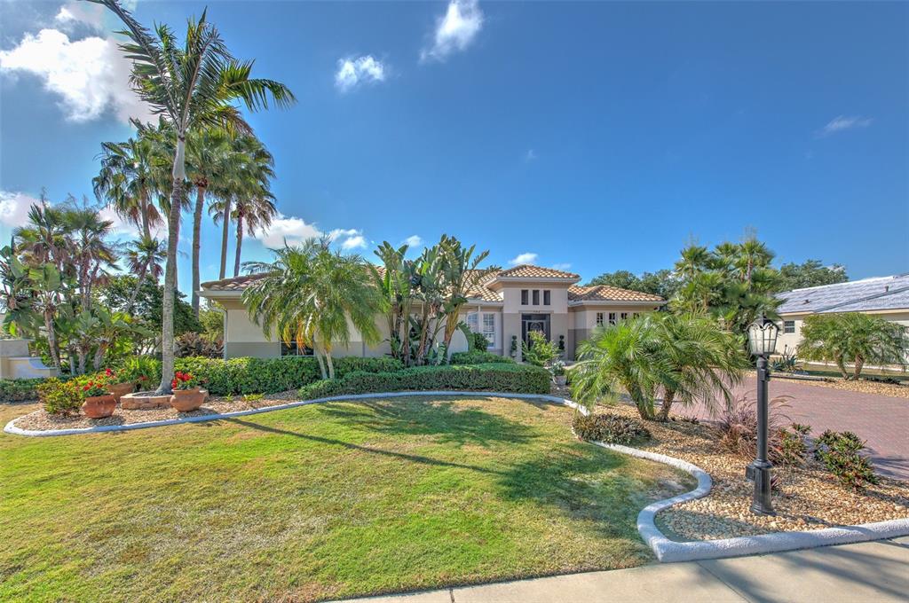 A single-story house with a tiled roof, palm trees, and a landscaped front lawn — 504 RIMINI VISTA WAY, SUN CITY CENTER, FL