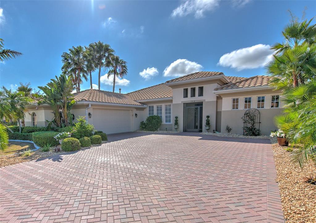 A single-story house with a tiled roof, a brick paver driveway, and palm trees — 504 RIMINI VISTA WAY, SUN CITY CENTER, FL