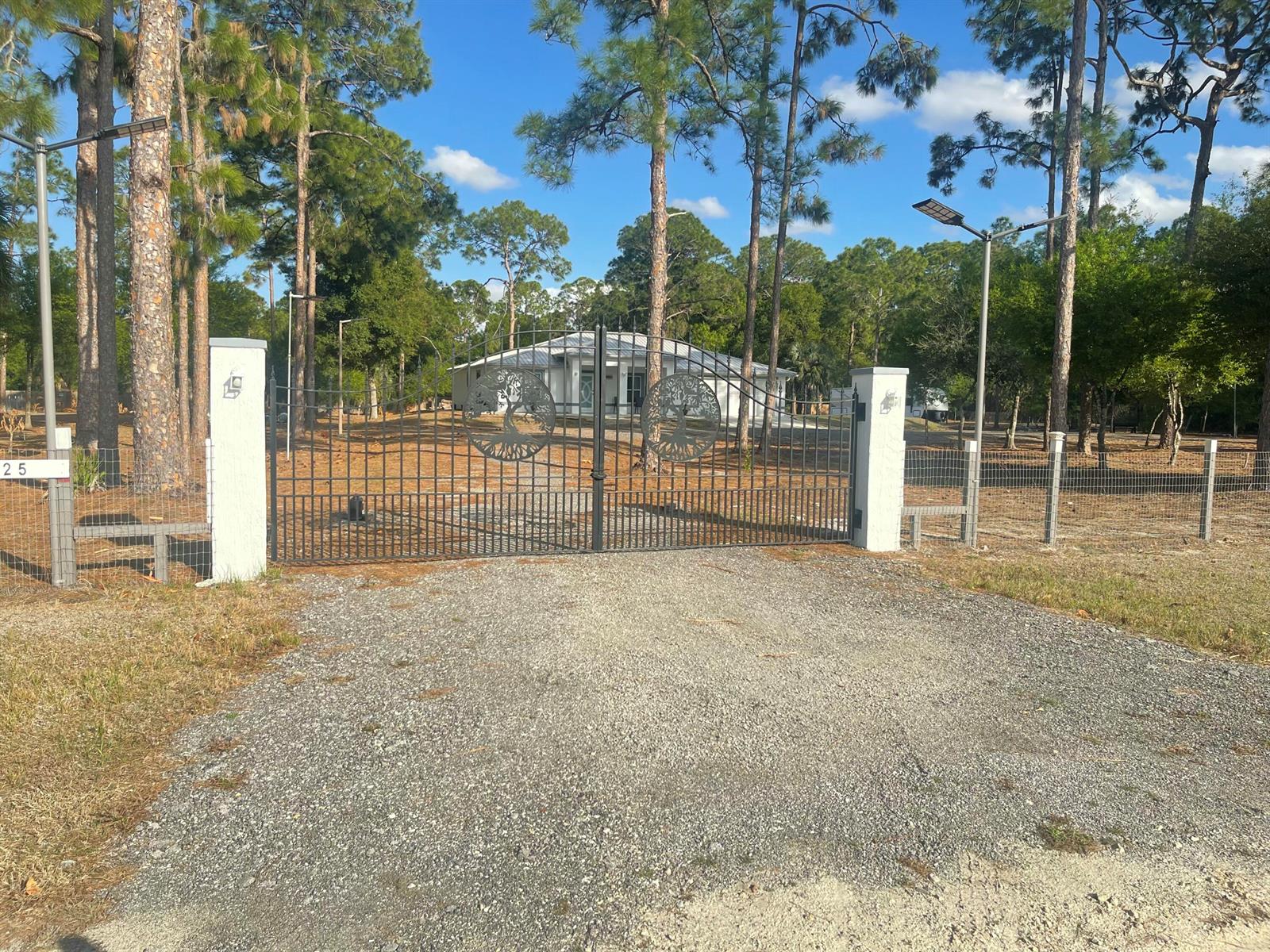 A gravel driveway leads to a gated entrance with a house visible in the background — 5325 Pioneer 17th Street, Clewiston FL 33440, CLEWISTON, FL