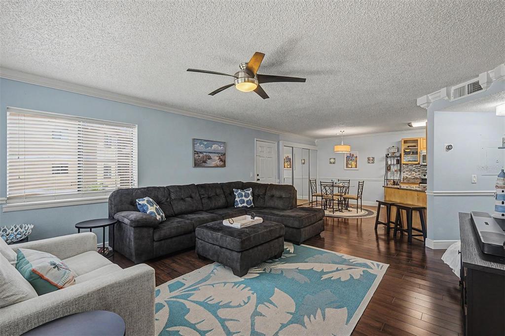A living room features a dark sectional sofa, a blue patterned rug, and hardwood floors — 1550 S BELCHER ROAD UNIT 525, CLEARWATER, FL