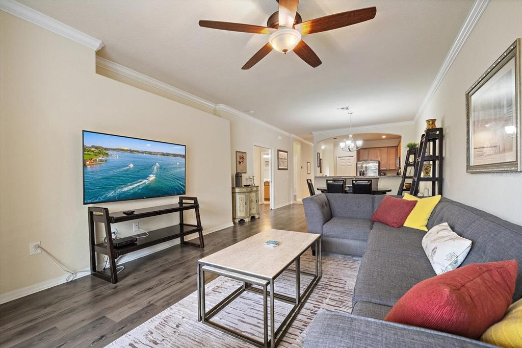 A living room features a grey sectional sofa, a coffee table, and a wall-mounted television — 19962 BENISSIMO DRIVE, VENICE, FL