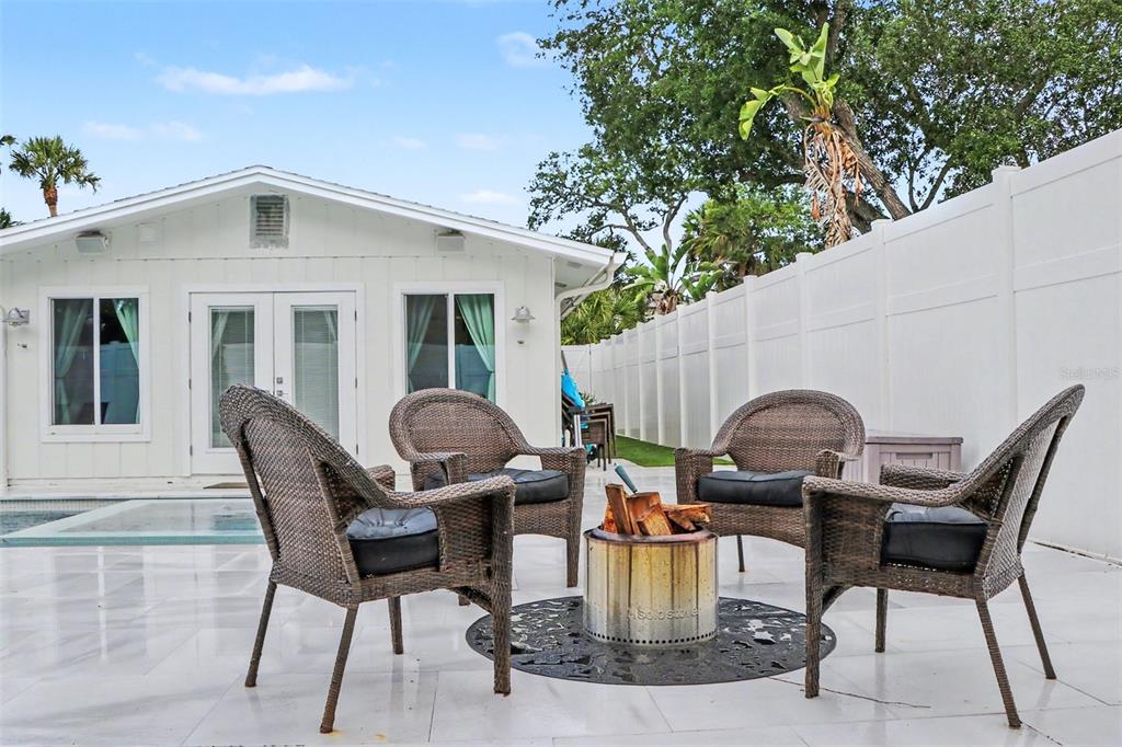 A modern backyard features a rectangular swimming pool with lounge chairs and a covered patio area — 5143 SANDY BEACH AVENUE, SARASOTA, FL