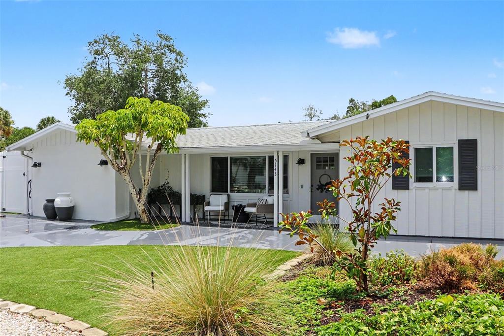 A patio features four wicker chairs arranged around a metal fire pit on white tiles — 5143 SANDY BEACH AVENUE, SARASOTA, FL
