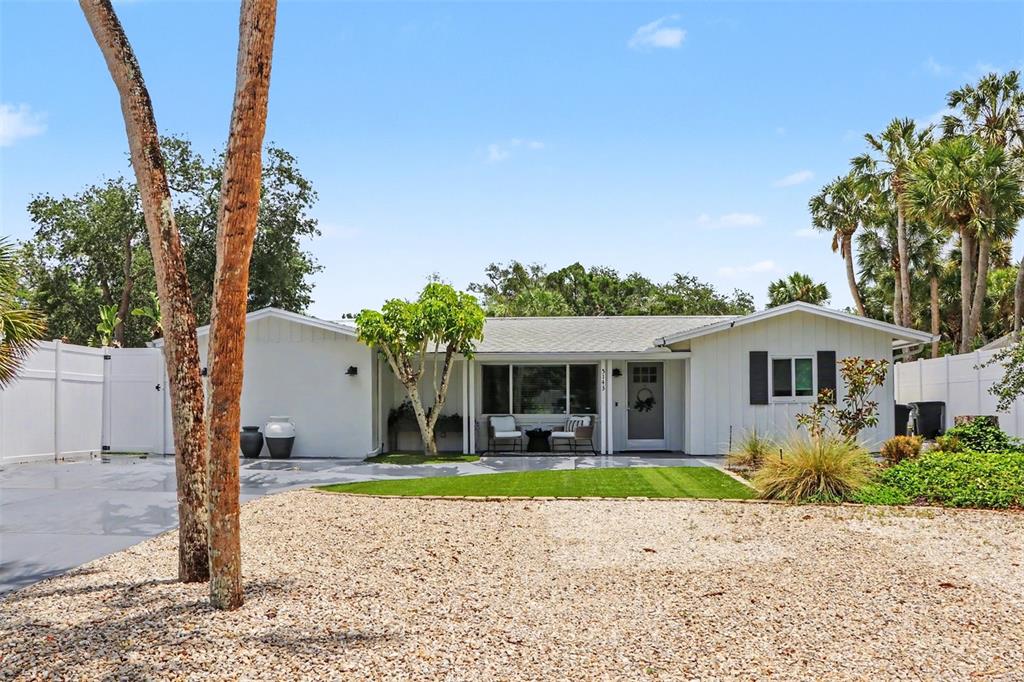 A single-story house with white vertical siding, a gravel front yard, and palm trees — 5143 SANDY BEACH AVENUE, SARASOTA, FL