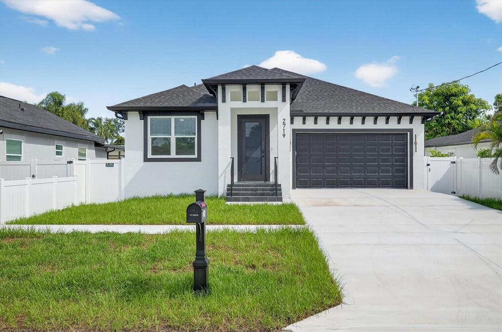 A single-story house with a white stucco exterior, dark trim, and a two-car garage — 2719 W SAINT JOHN STREET, TAMPA, FL