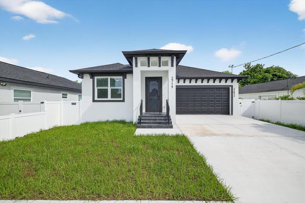 A single-story house with white stucco walls, a dark roof, and a front-facing garage — 2719 W SAINT JOHN STREET, TAMPA, FL