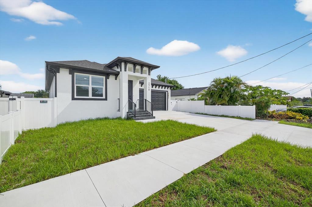 A white single-story house with a dark trim, front porch, and a concrete driveway — 2719 W SAINT JOHN STREET, TAMPA, FL