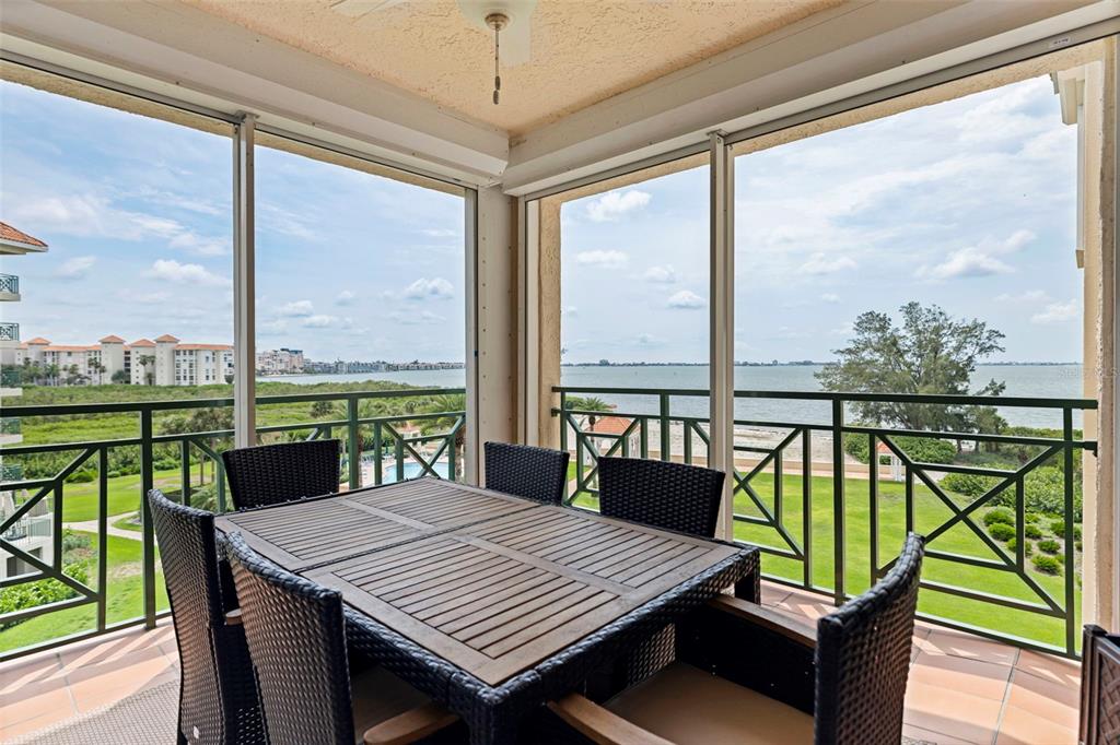 A screened-in balcony features a dining set overlooking a grassy lawn and a large bay — 4737 DOLPHIN CAY LANE S UNIT 401, ST PETERSBURG, FL