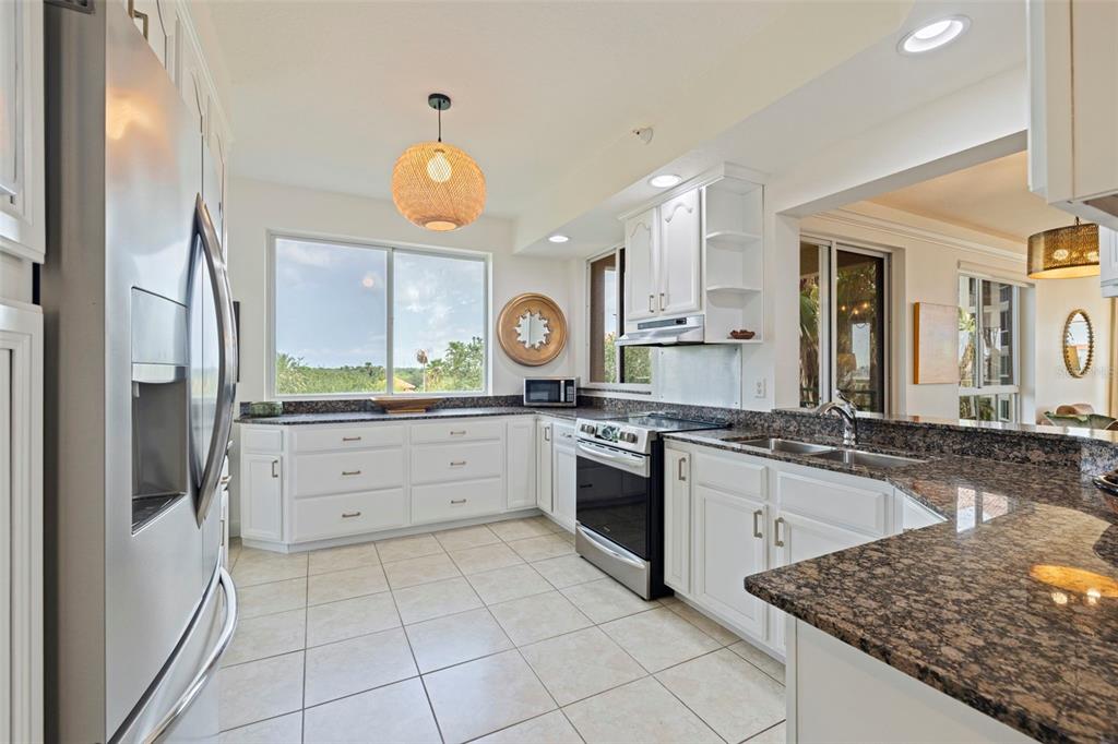 A kitchen with white cabinets, granite countertops, stainless steel appliances, and a large window — 4737 DOLPHIN CAY LANE S UNIT 401, ST PETERSBURG, FL