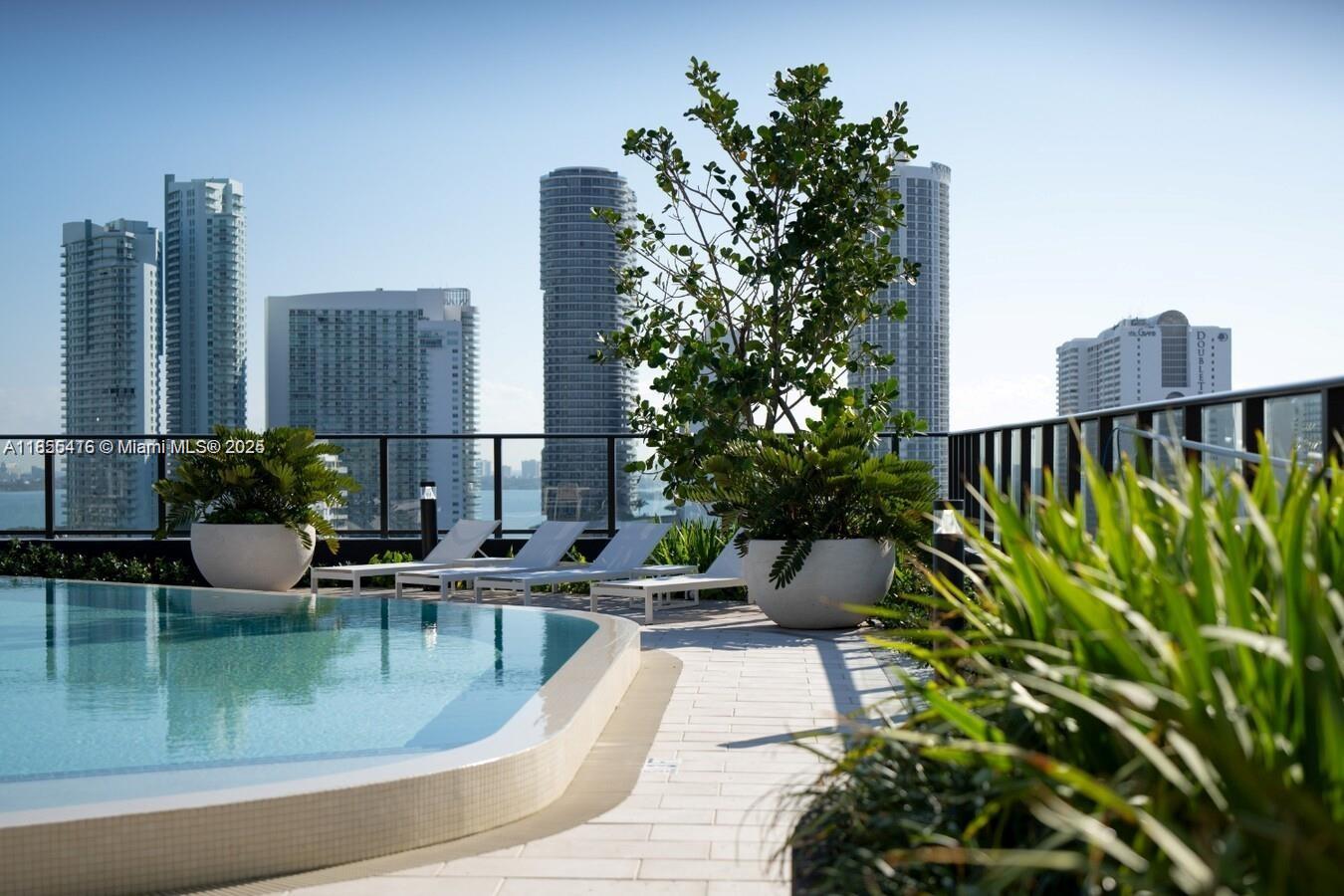 A rooftop swimming pool area features lounge chairs, potted plants, and views of city skyscrapers — 23 NE 17th Ter, Miami FL 33132, MIAMI, FL