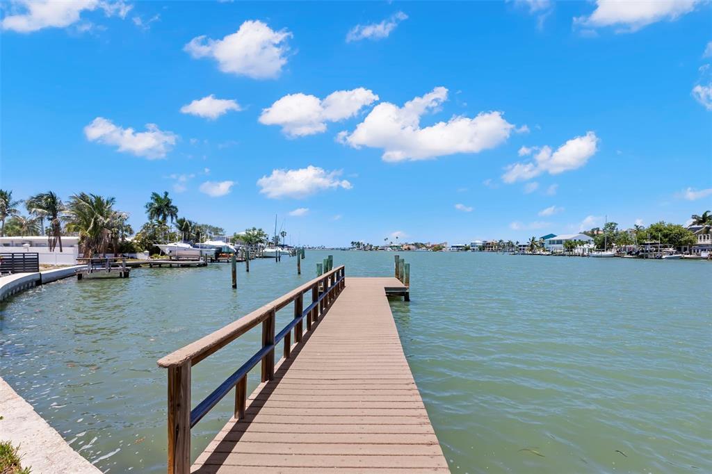 A waterfront house with a private dock, a grassy yard, and a modern shed roof — 708 SUNSET COVE, MADEIRA BEACH, FL