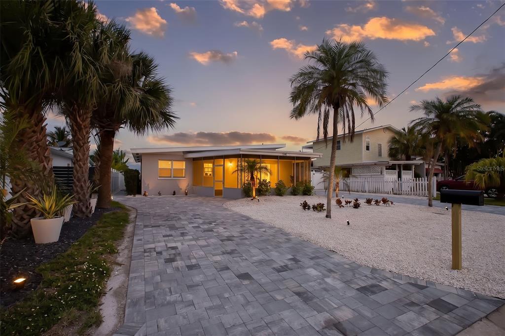 A wooden dock extends into a calm waterway under a bright blue sky — 708 SUNSET COVE, MADEIRA BEACH, FL