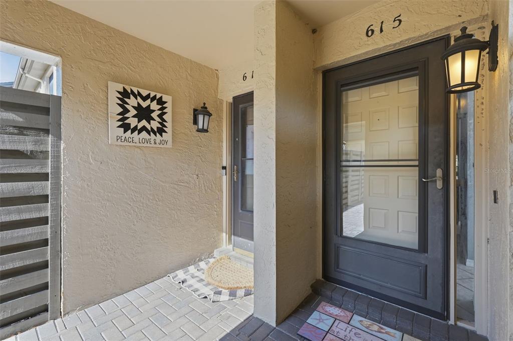 The exterior entryway features two dark-framed glass doors with house numbers and wall-mounted lanterns — 3163 LANDMARK DRIVE UNIT 615, CLEARWATER, FL