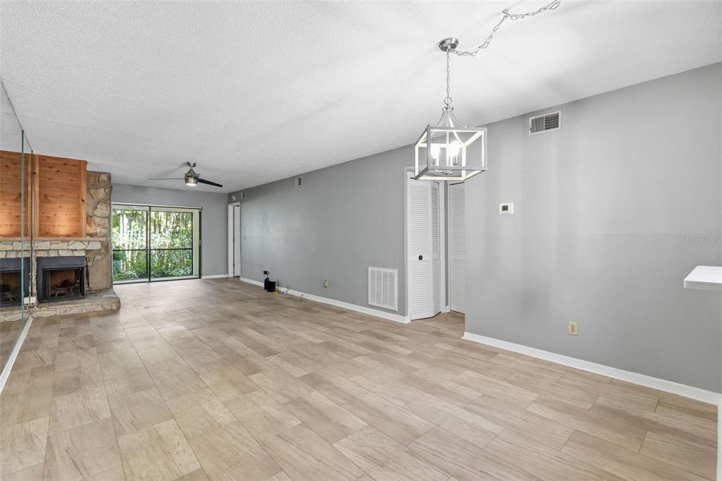 A living room with light wood-look flooring, a stone fireplace, and a modern pendant light — 3163 LANDMARK DRIVE UNIT 615, CLEARWATER, FL