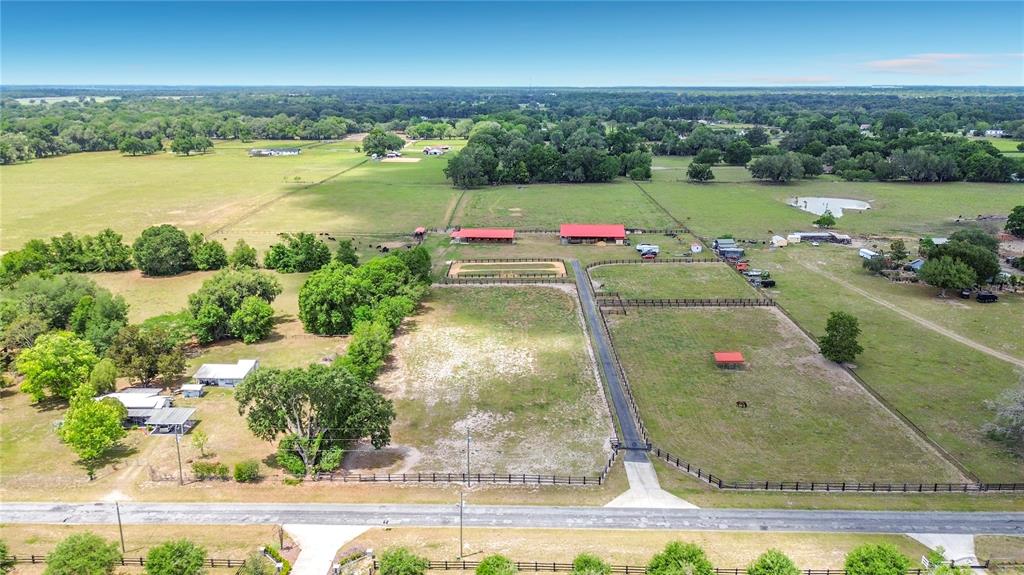 An aerial view shows a rural property with a house, barns, and fenced pastures — 16750 SE 19TH COURT, SUMMERFIELD, FL