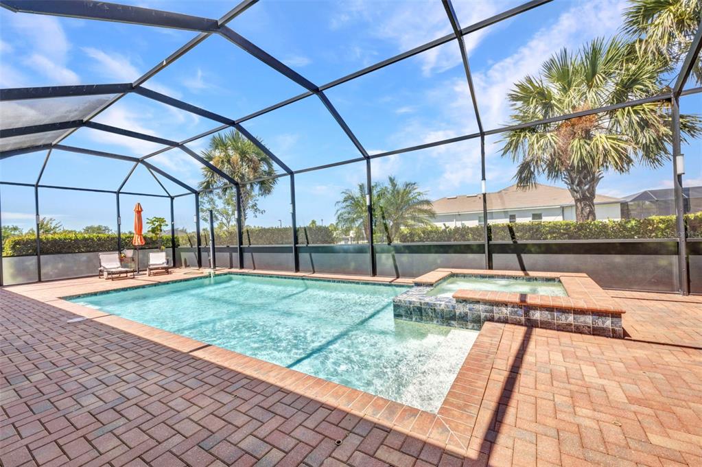 A screened-in swimming pool and hot tub on a brick patio with palm trees nearby — 15000 SPANISH POINT DRIVE, PORT CHARLOTTE, FL