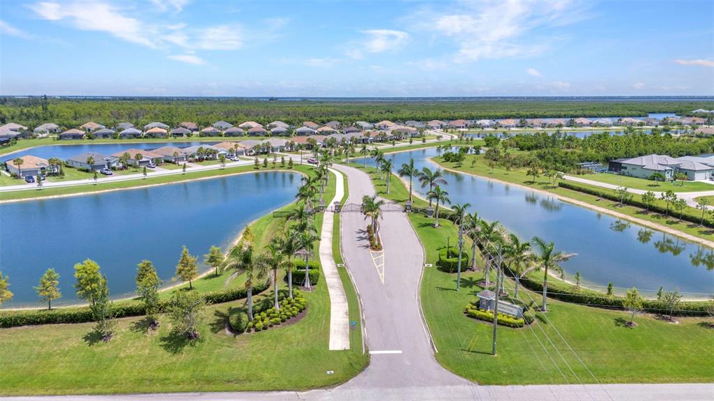 An aerial view shows a gated residential community entrance flanked by two large ponds — 15000 SPANISH POINT DRIVE, PORT CHARLOTTE, FL