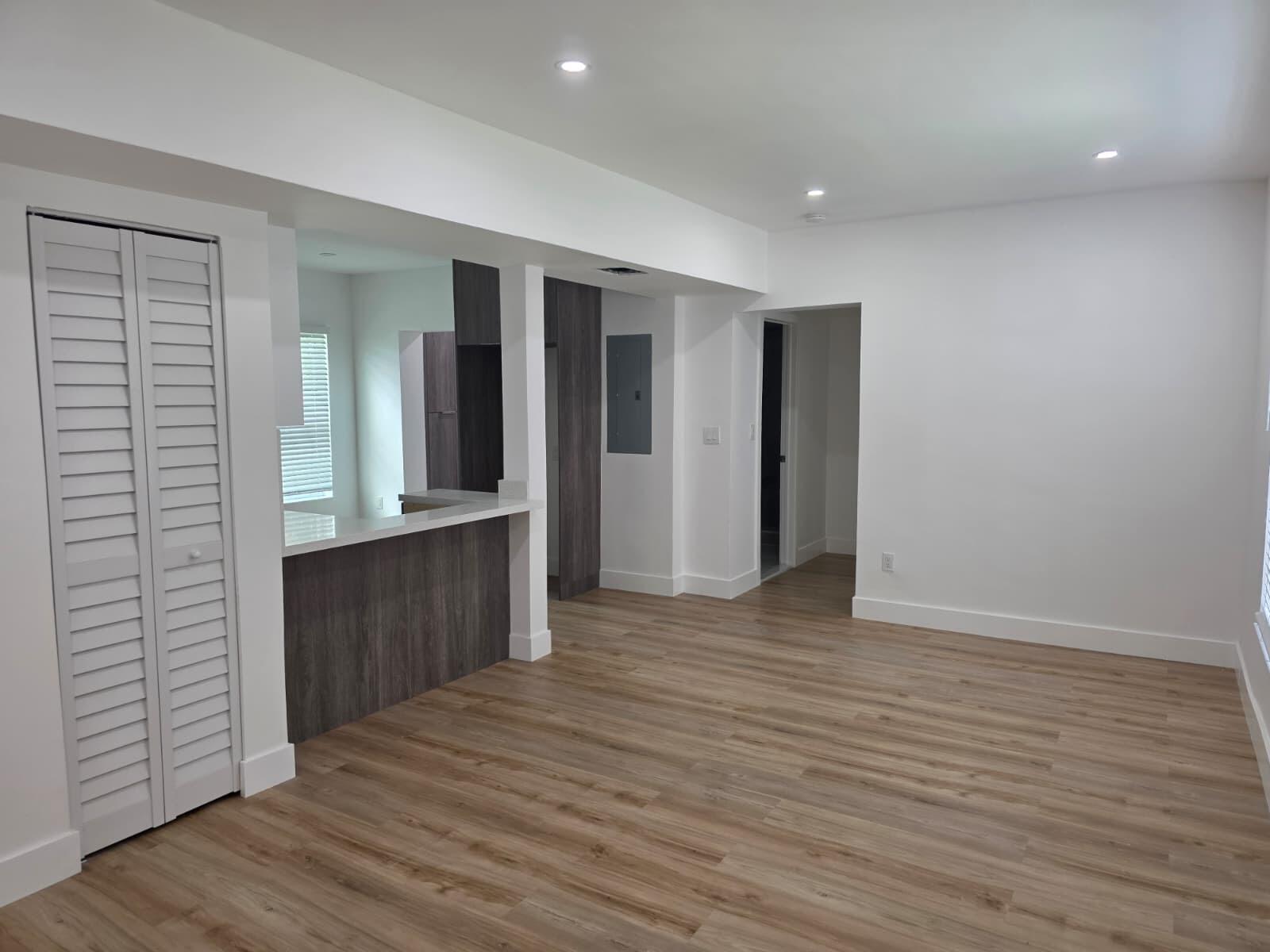 An unfurnished room with light wood-look flooring, white walls, recessed lighting, and a kitchen pass-through — 9900 NW 25th Avenue, Miami FL 33147, MIAMI, FL