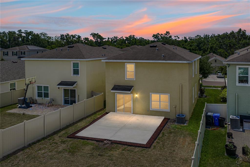 An aerial view of the backyards and rear exterior of two-story suburban homes at sunset — 16833 TRITE BEND STREET, WIMAUMA, FL