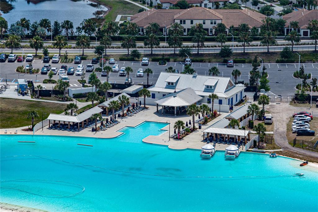 An aerial view shows a large turquoise swimming pool, a clubhouse, and a parking lot — 16833 TRITE BEND STREET, WIMAUMA, FL