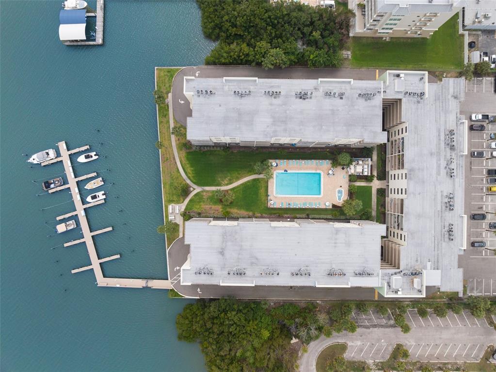 An aerial view shows a waterfront apartment complex with a central pool and boat docks — 19531 GULF BOULEVARD UNIT 414, INDIAN SHORES, FL