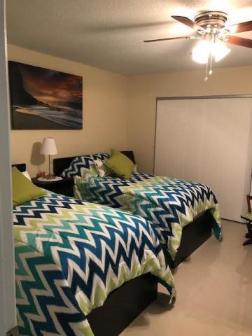A bedroom features two twin beds with chevron-patterned bedding and a ceiling fan — 3300 Springdale Boulevard # 301, Palm Springs FL 33461, PALM SPRINGS, FL