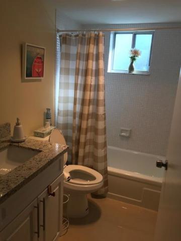 A bathroom features a granite vanity, a toilet, and a bathtub with a plaid shower curtain — 3300 Springdale Boulevard # 301, Palm Springs FL 33461, PALM SPRINGS, FL