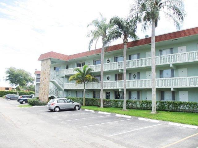 A three-story apartment building with a stone accent wall, balconies, and a parking lot — 3300 Springdale Boulevard # 301, Palm Springs FL 33461, PALM SPRINGS, FL