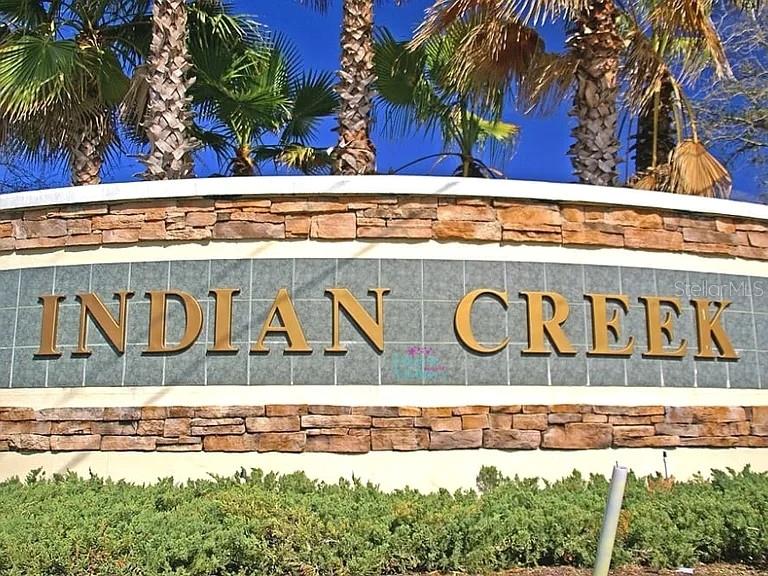 A stone monument sign with gold lettering reads Indian Creek beneath palm trees — 2672 AUTUMN CREEK CIRCLE, KISSIMMEE, FL
