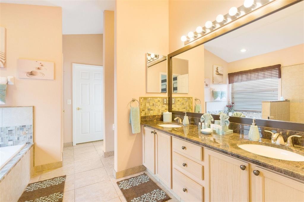 A bathroom features a double vanity with granite countertops, light wood cabinets, and a large mirror — 2672 AUTUMN CREEK CIRCLE, KISSIMMEE, FL