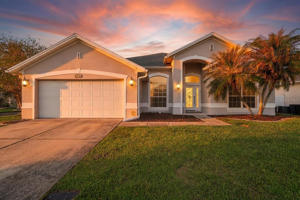 A single-story suburban house with a two-car garage, arched entryway, and a palm tree — 2716 WORTHAM LANE, KISSIMMEE, FL
