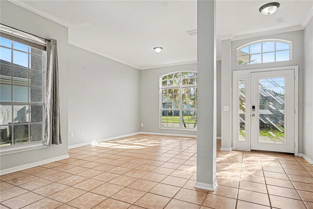 A bright, tiled entryway and living area featuring a front door and large arched windows — 2716 WORTHAM LANE, KISSIMMEE, FL