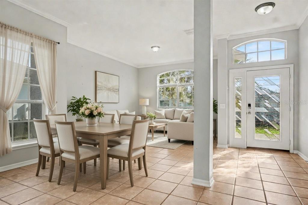A dining area and living room feature tile floors, neutral furniture, and a front entryway — 2716 WORTHAM LANE, KISSIMMEE, FL