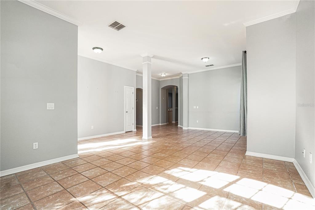 An open-concept living area features light gray walls, tile flooring, and a central support column — 2716 WORTHAM LANE, KISSIMMEE, FL