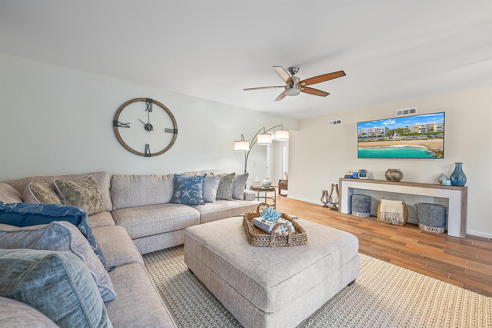 A living room features a large sectional sofa, a central ottoman, and a wall-mounted television — 16695 Traders Crossing N # 118, Jupiter FL 33477, JUPITER, FL