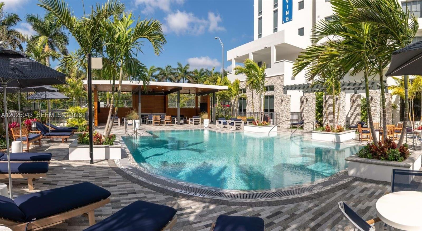 A swimming pool with lounge chairs and a covered patio area at a modern building — 4720 NW 85th Ave # A2, Doral FL 33166, DORAL, FL