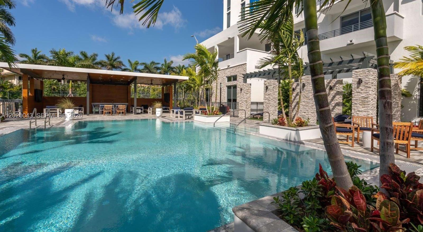 An outdoor swimming pool area features a covered patio, lounge seating, and palm trees — 4720 NW 85th Ave # A2, Doral FL 33166, DORAL, FL