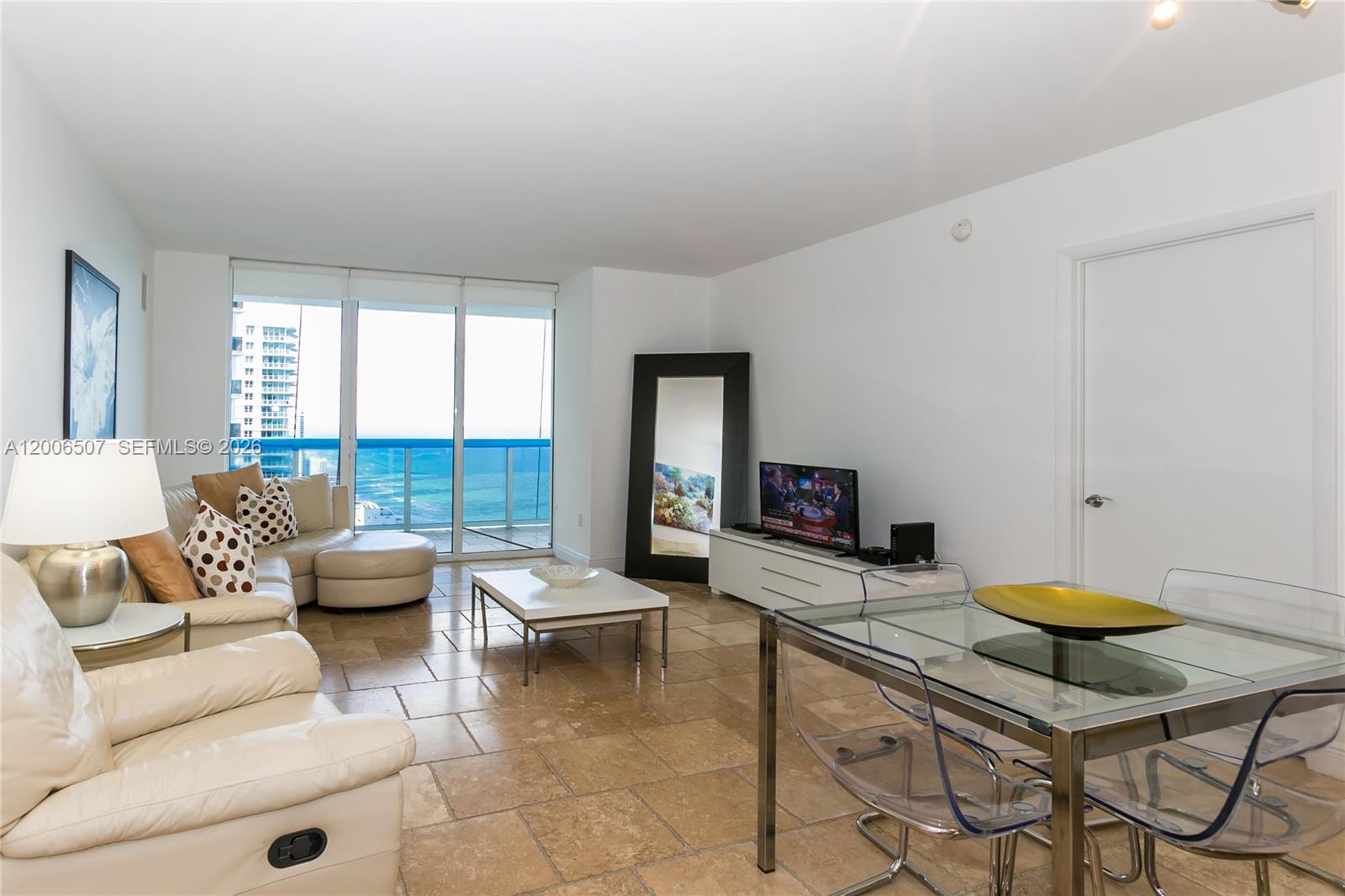 A living and dining area features tile floors, white furniture, and a balcony with ocean views — 1830 S OCEAN DR # 4010, Hallandale Beach FL 33009, HALLANDALE BEACH, FL