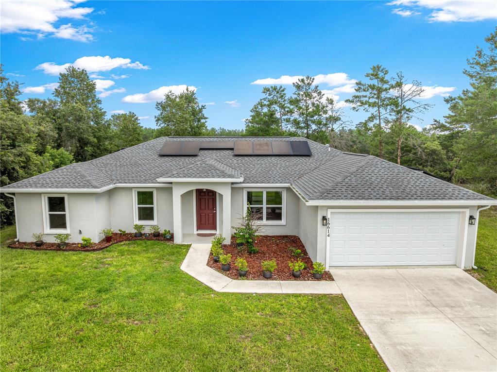 A single-story house with a gray exterior, a two-car garage, and solar panels on the roof — 16614 SW 45TH CIRCLE, OCALA, FL