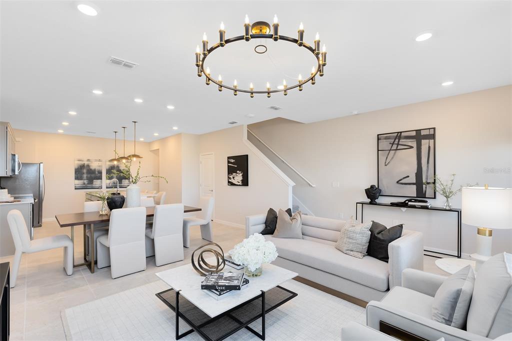 An open-concept living and dining area features a large circular chandelier, neutral furniture, and tile floors — 11571 HARBORVIEW STREET, ORLANDO, FL