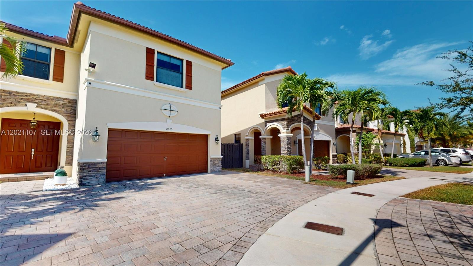 A two-story house with a beige stucco exterior, stone accents, and a paved driveway — 8610 NW 101st Pl, Doral FL 33178, DORAL, FL