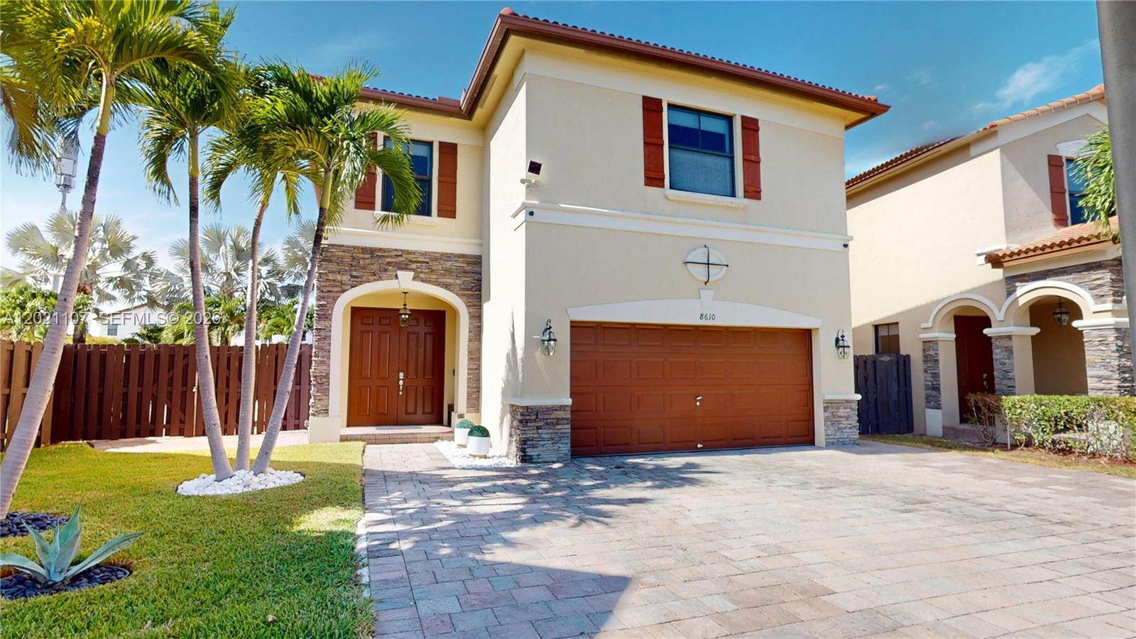 A two-story house features a tan stucco exterior, stone accents, and a double garage — 8610 NW 101st Pl, Doral FL 33178, DORAL, FL