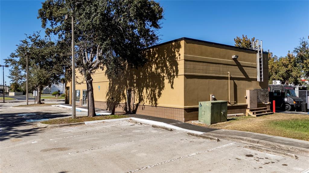 A tan commercial building with a parking lot and a large tree in the foreground — 7155 S ORANGE BLOSSOM TRAIL, ORLANDO, FL