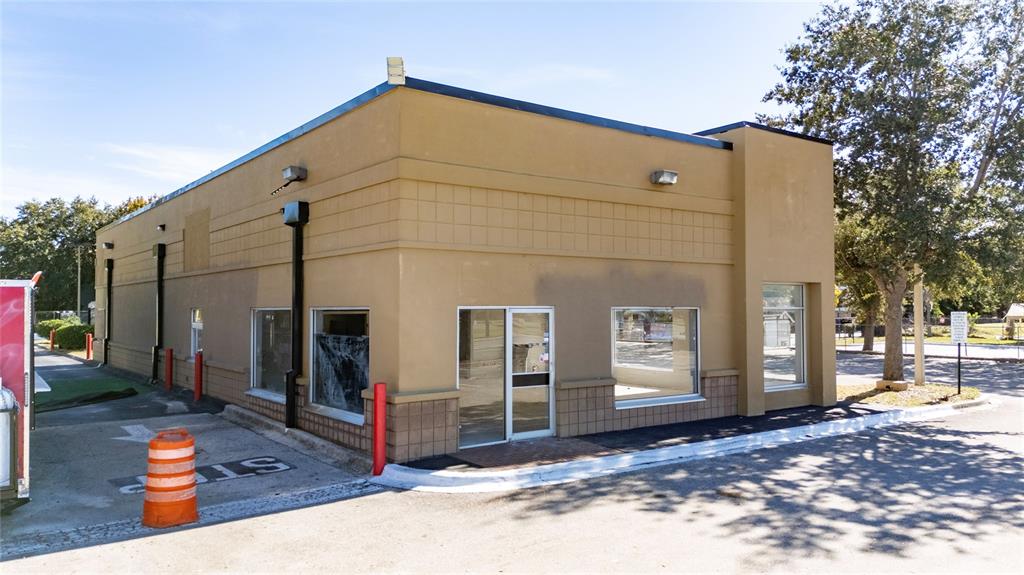 A tan commercial building with large windows and a glass entrance door sits outdoors — 7155 S ORANGE BLOSSOM TRAIL, ORLANDO, FL