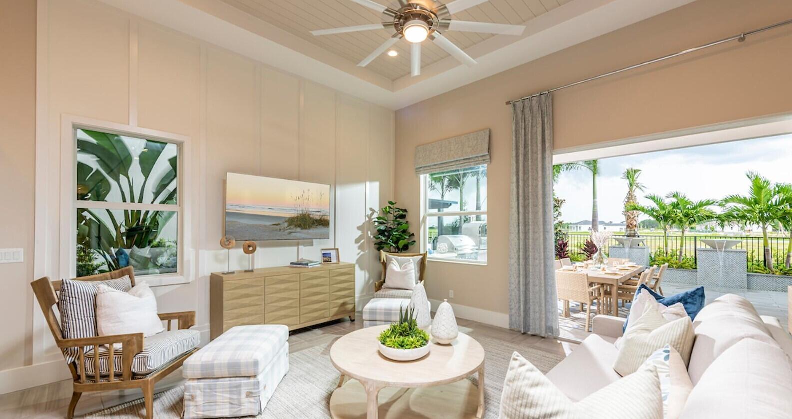 A bright living room features a tray ceiling, a television, and sliding doors to a patio — 9858 Regency Way, Palm Beach Gardens FL 33412, PALM BEACH GARDENS, FL