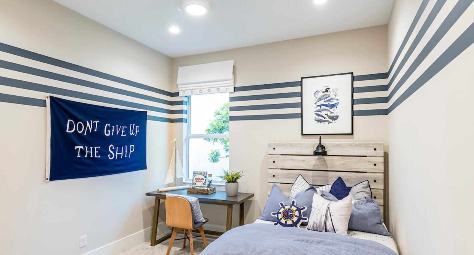 A nautical-themed bedroom features striped walls, a wooden headboard, and a desk by the window — 9858 Regency Way, Palm Beach Gardens FL 33412, PALM BEACH GARDENS, FL