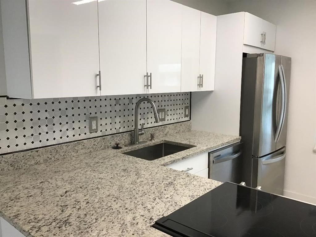 A kitchen featuring white cabinets, granite countertops, a stainless steel sink, and a patterned backsplash — 7600 NW 4th Place # 207, Margate FL 33063, MARGATE, FL