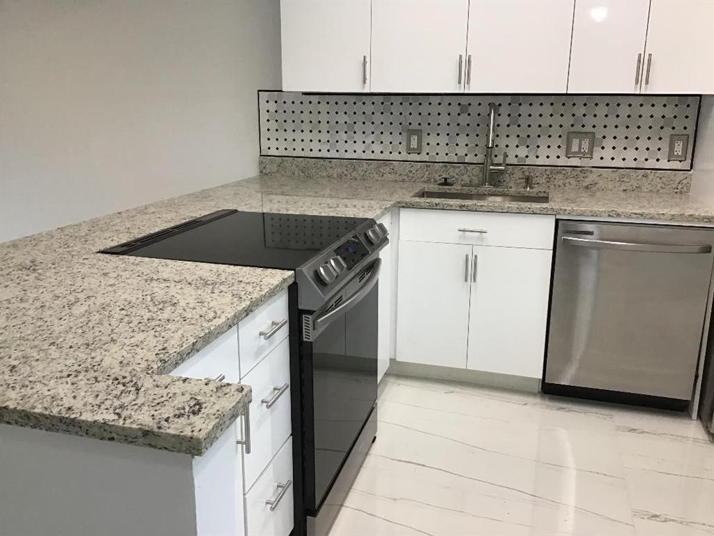 A kitchen features white cabinets, granite countertops, a stainless steel stove, and a tiled backsplash — 7600 NW 4th Place # 207, Margate FL 33063, MARGATE, FL