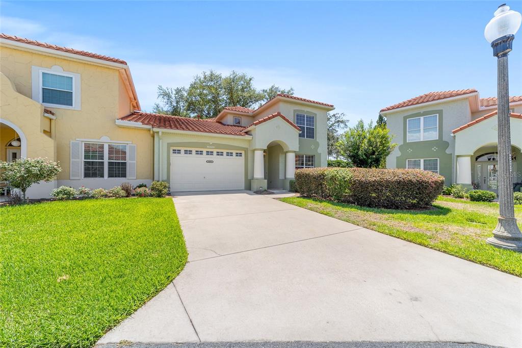 A two-story suburban house with a concrete driveway, garage, and a street lamp — 1074 AVENIDA SONOMA, LADY LAKE, FL